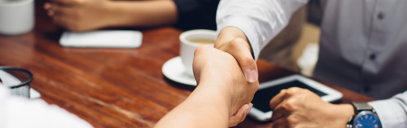 Two people shaking hands over coffee